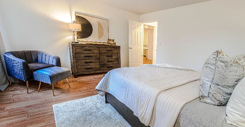 Primary bedroom with queen bed, dresser, mirror, and sitting area